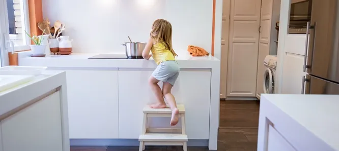 Guía básica de seguridad de bebés y niños en casa Niña en cocinando encima de un butaca