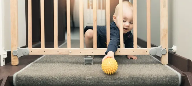 Guía de seguridad para las casas con bebés y niños Bebé alcanzando pelota en reja de seguridad